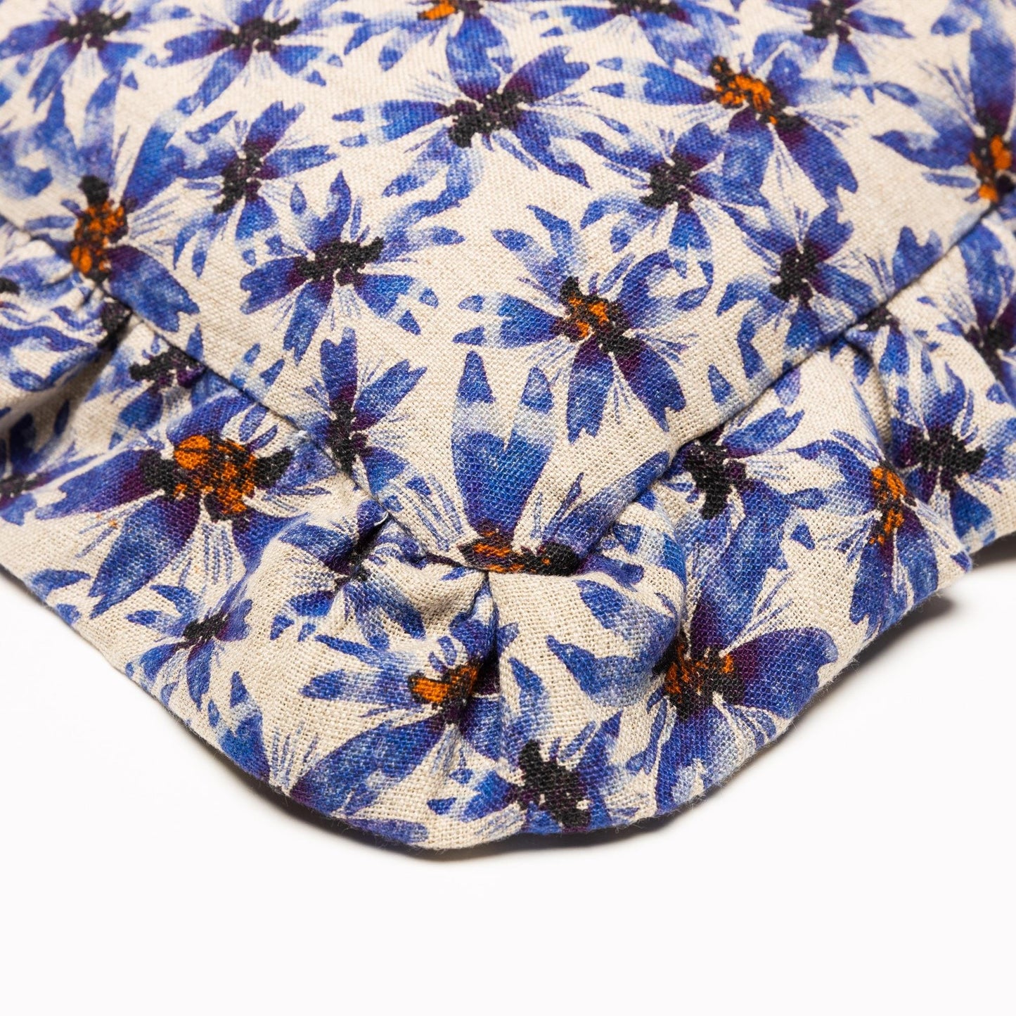 Closeup of corner of organic linen pillow with ruffles printed in whimsical blue florals.