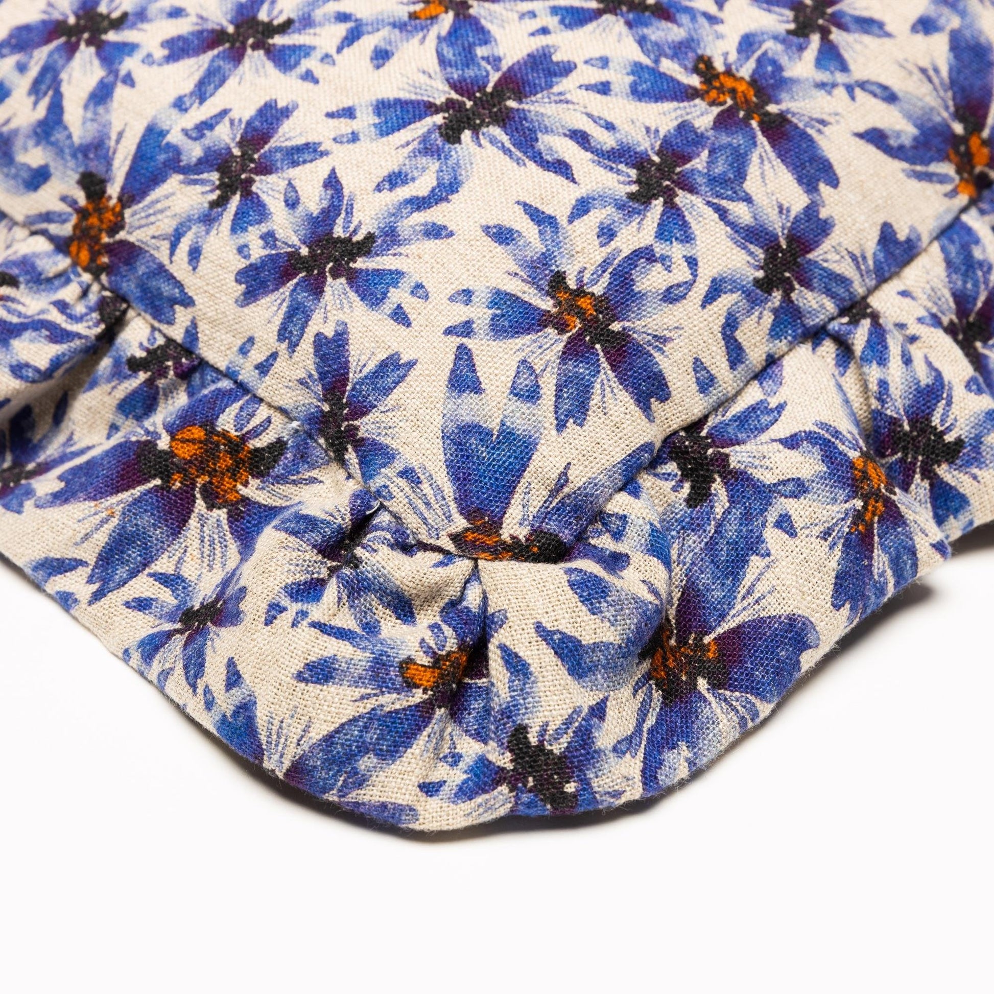 Closeup of corner of organic linen pillow with ruffles printed in whimsical blue florals.