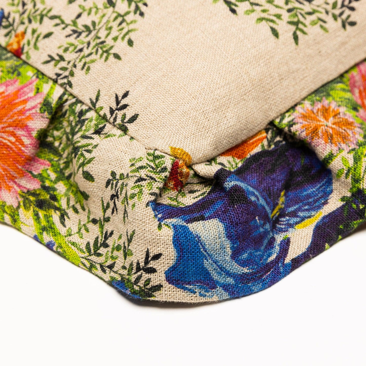 Corner closeup detail of a square ruffled pillow with bright floral print.