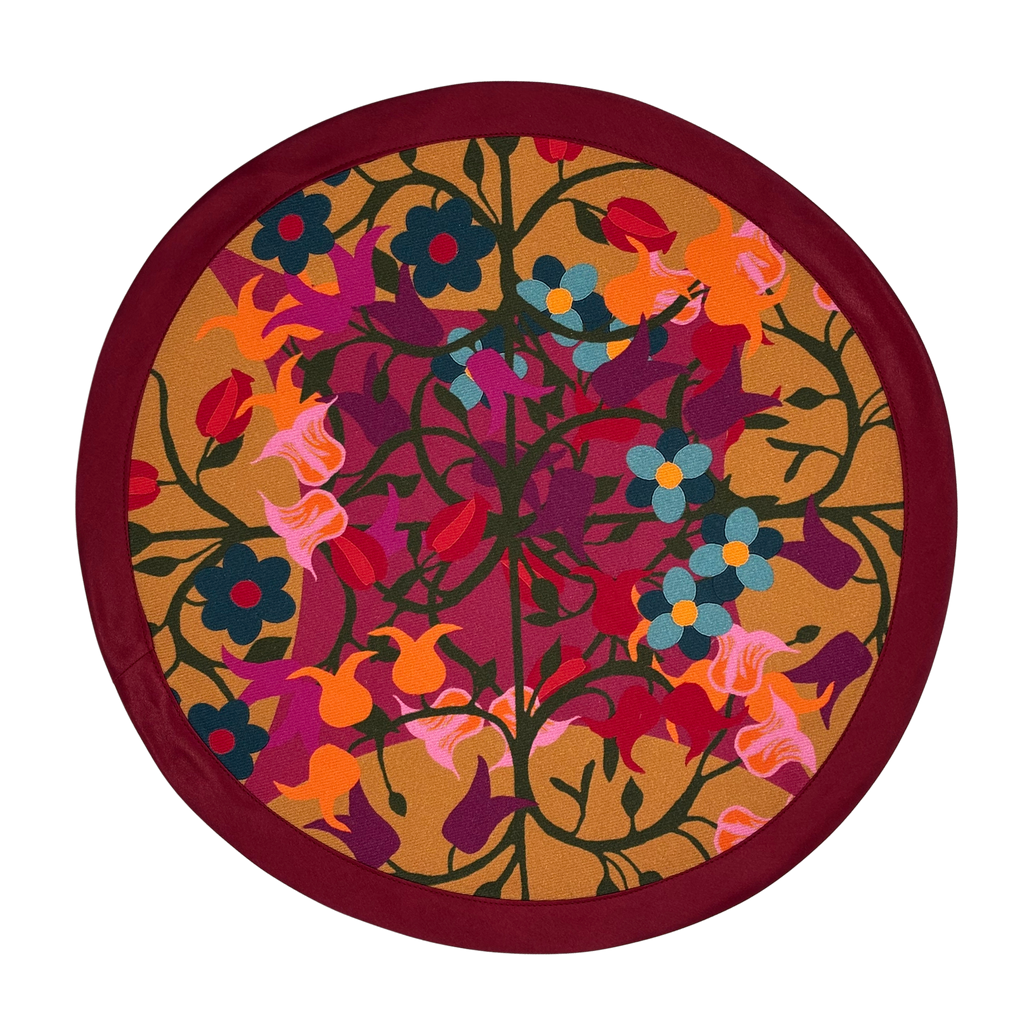 Round organic cotton placemat in orange and bordeaux floral geometric print.
