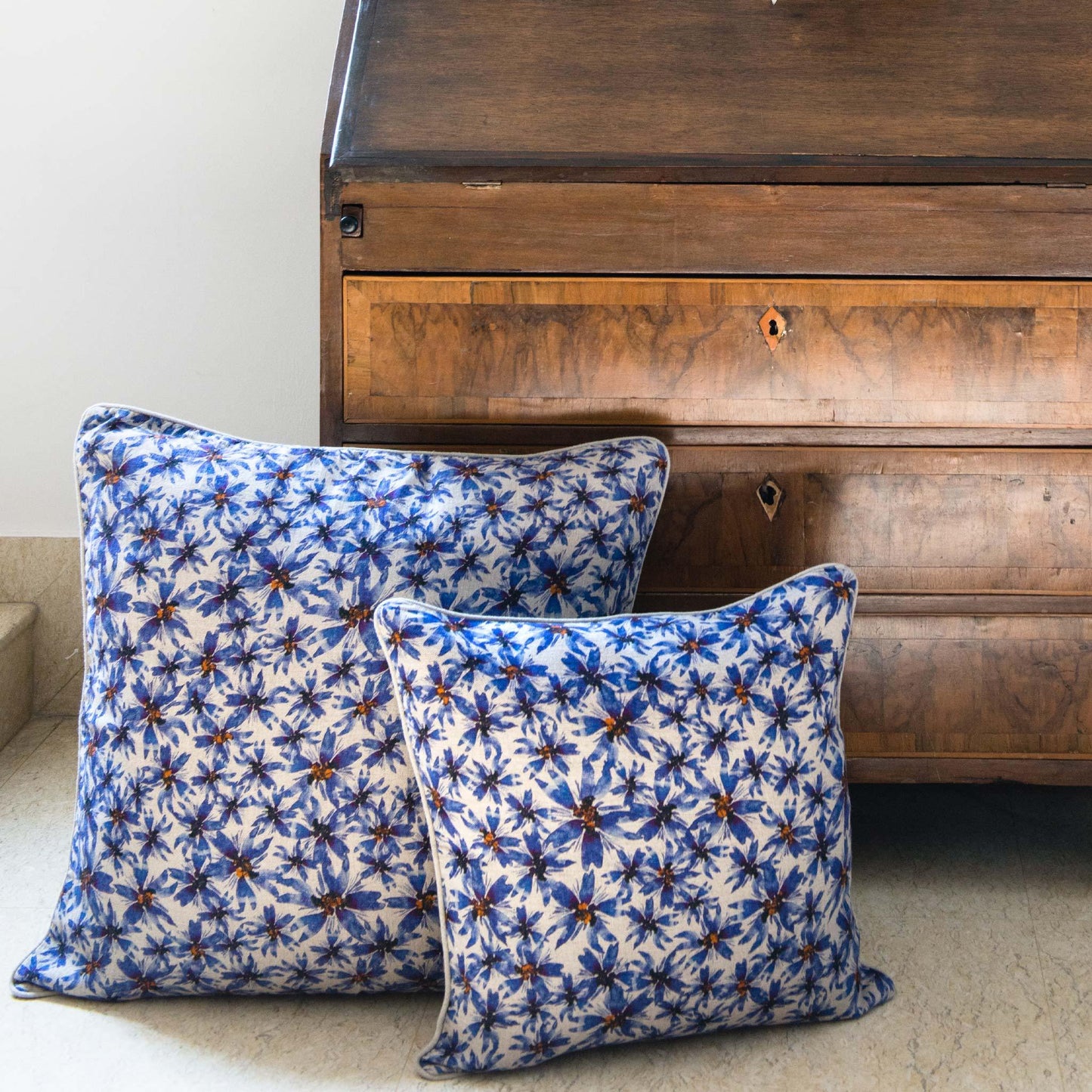 Blue illustrated flower print linen cushion covers in front of wooden desk.