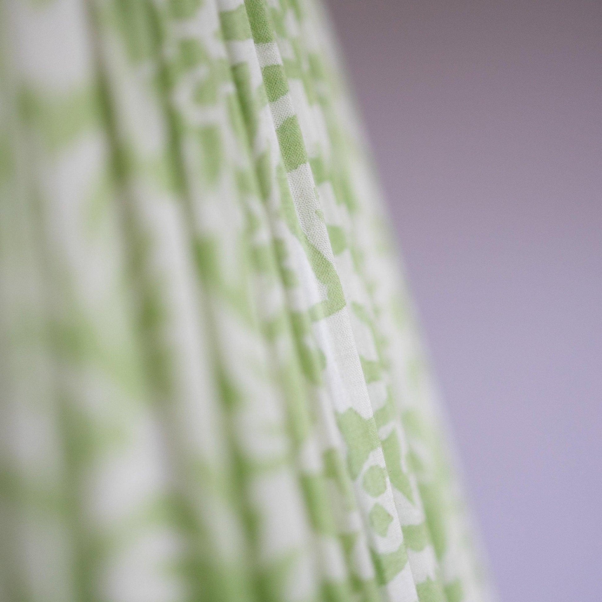 Closeup detail of hand block printed organic cotton in light green and white pattern.