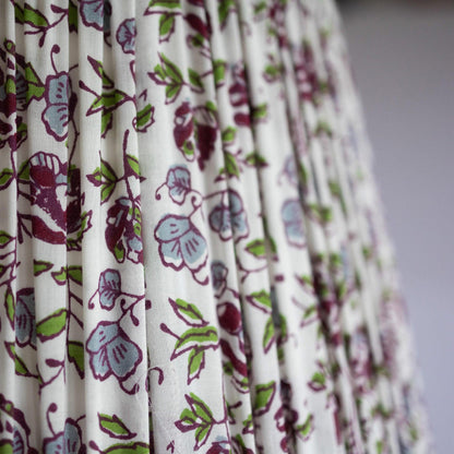 Closeup detail of hand block printed organic cotton in plum, green, purple and white lotus motif.