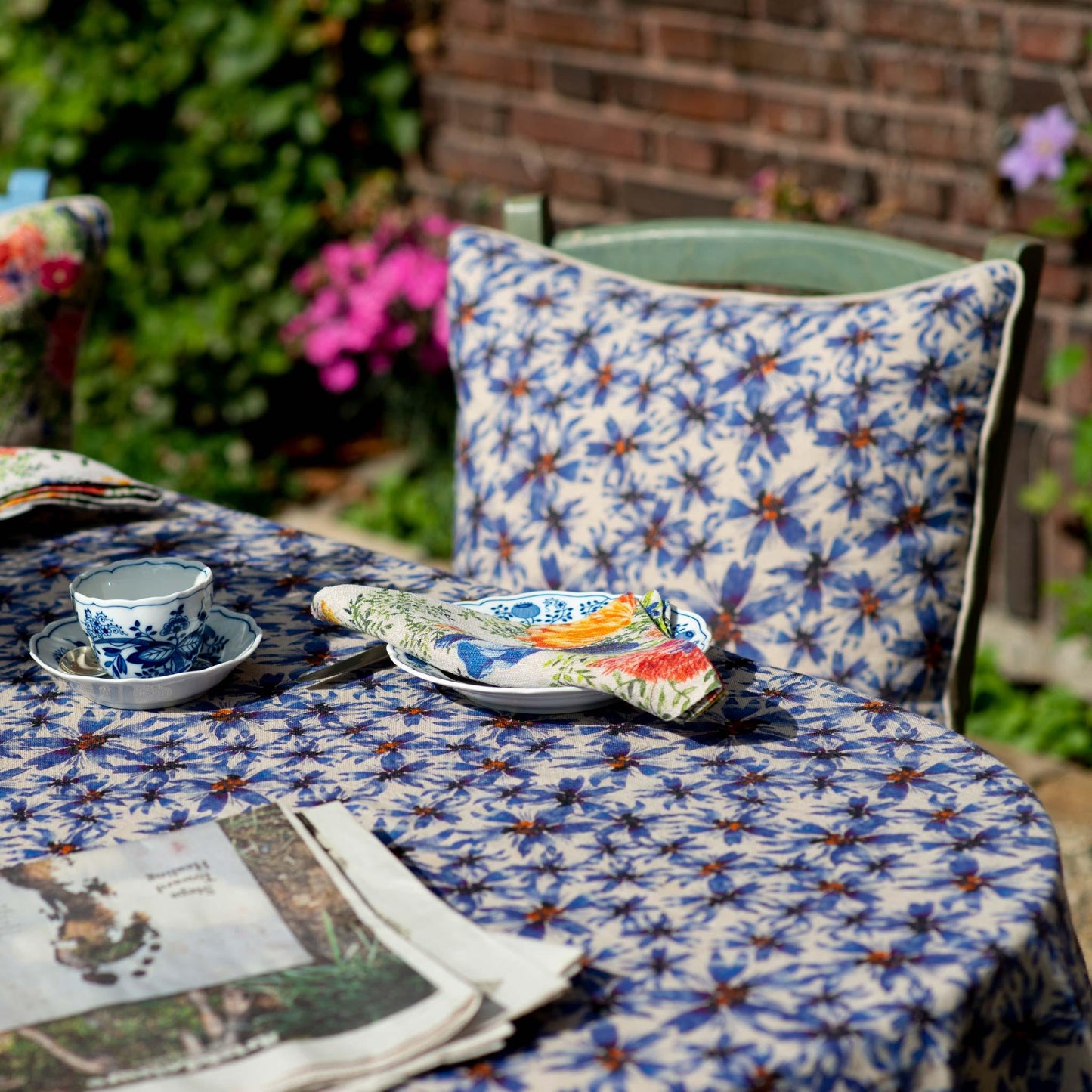Organic linen pillow cover printed with blue florals and an organic linen tablecloth in the same print.