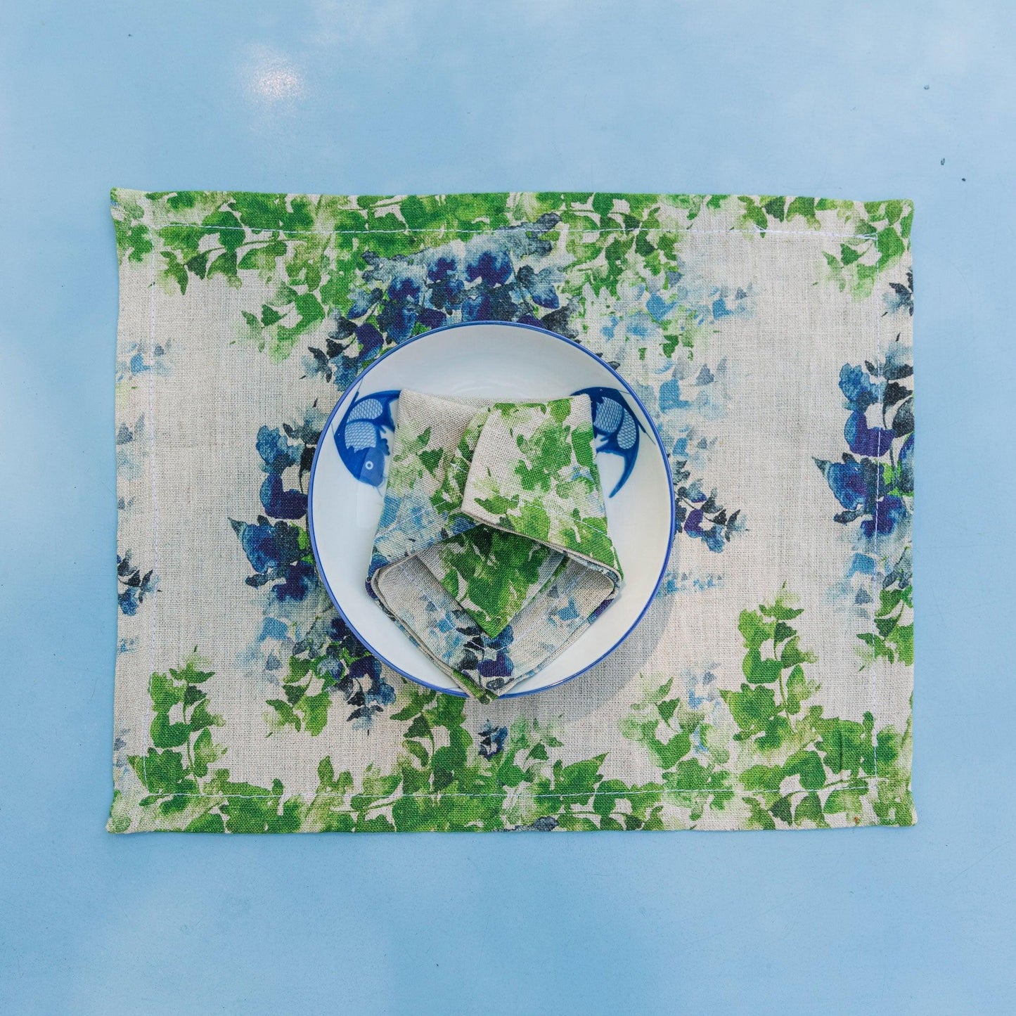 Table setting with organic linen placemat and napkin, printed with dreamy florals in blue and green, designed by Sophie Williamson Design.