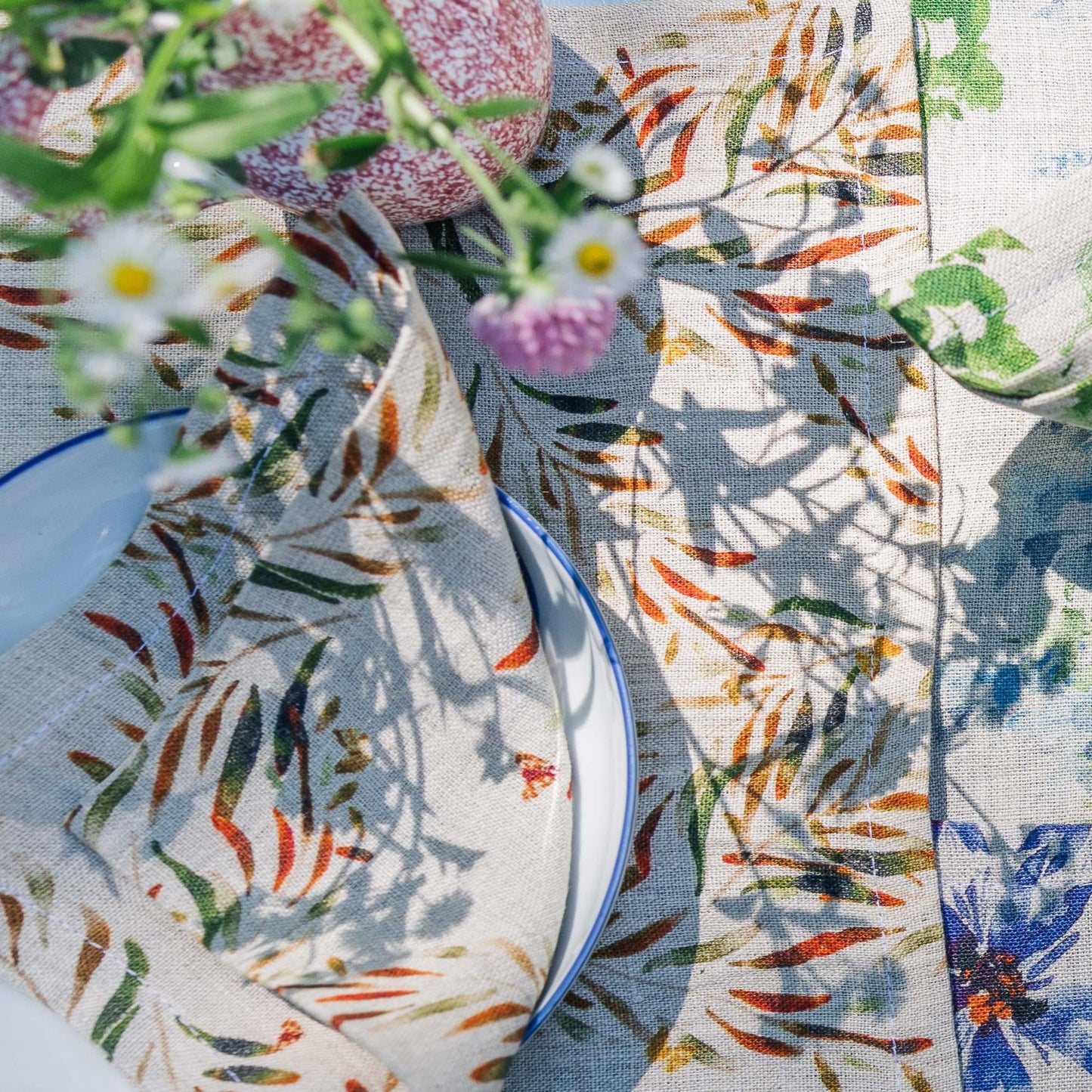 Close up of organic linen placemats and napkins, printed with colorful floral patterns, ethically made in India and USA, designed by Sophie Williamson Design.
