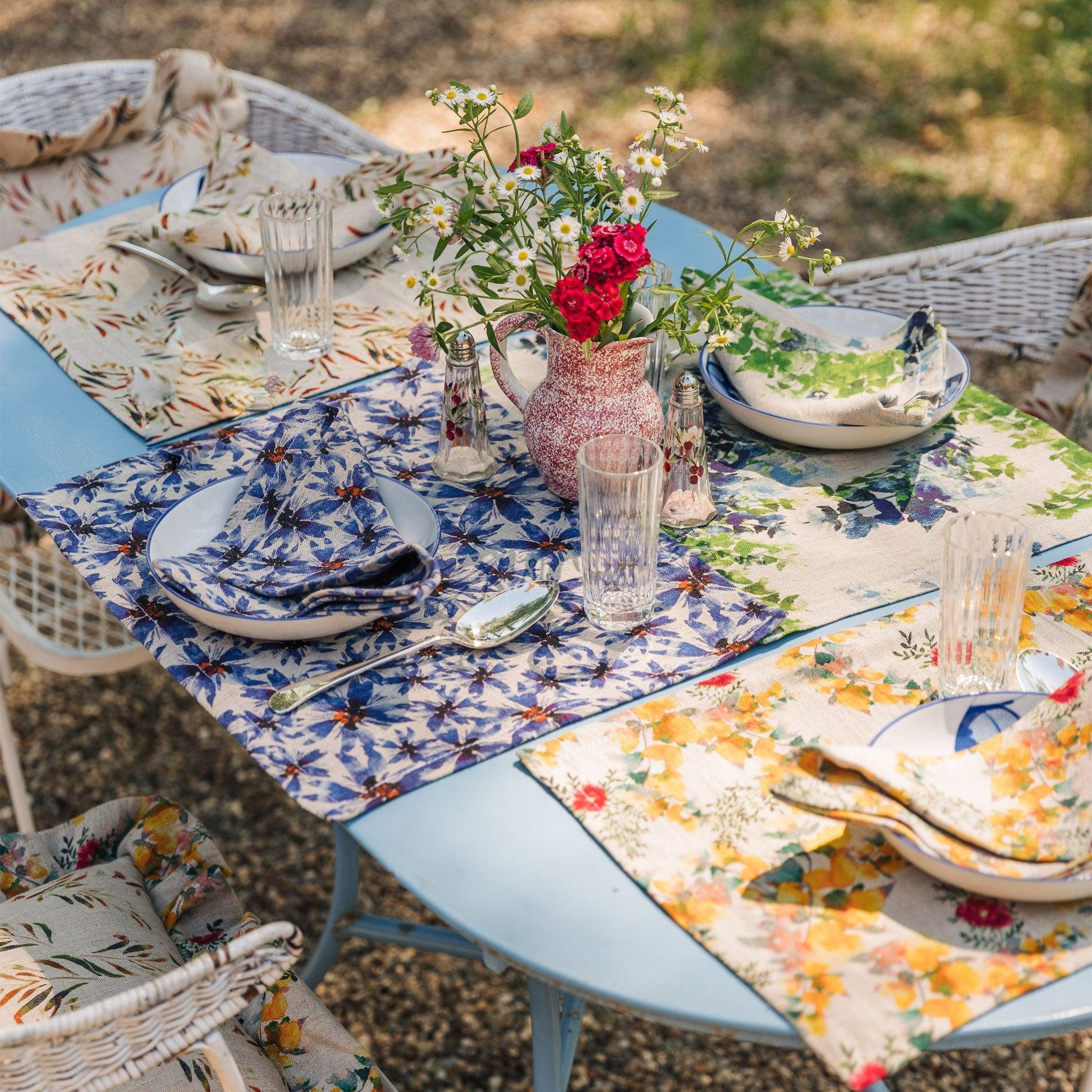 Outdoor table setting with floral napkins and placemats made of organic linen.