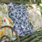 Three organic linen pillows with ruffles on an outdoor bench in a romantic setting.